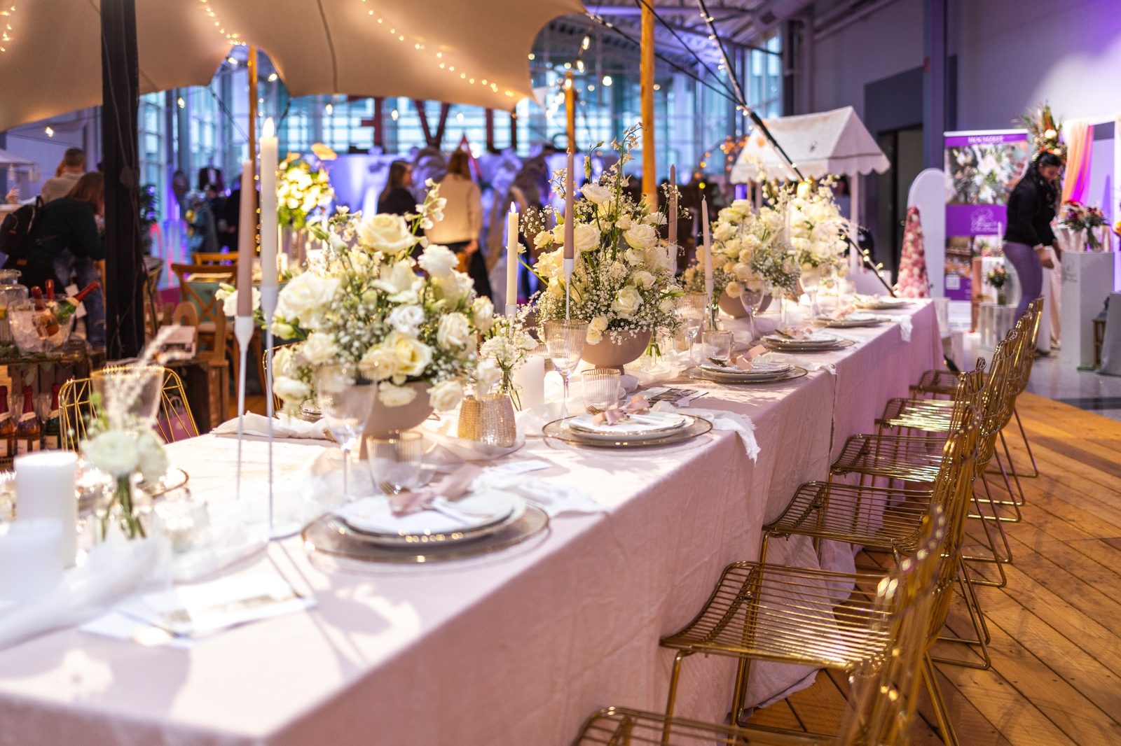 Stimmungsvoller Eindruck einer Messe mit festlich gedeckter Tafel, Blumen und Besuchern